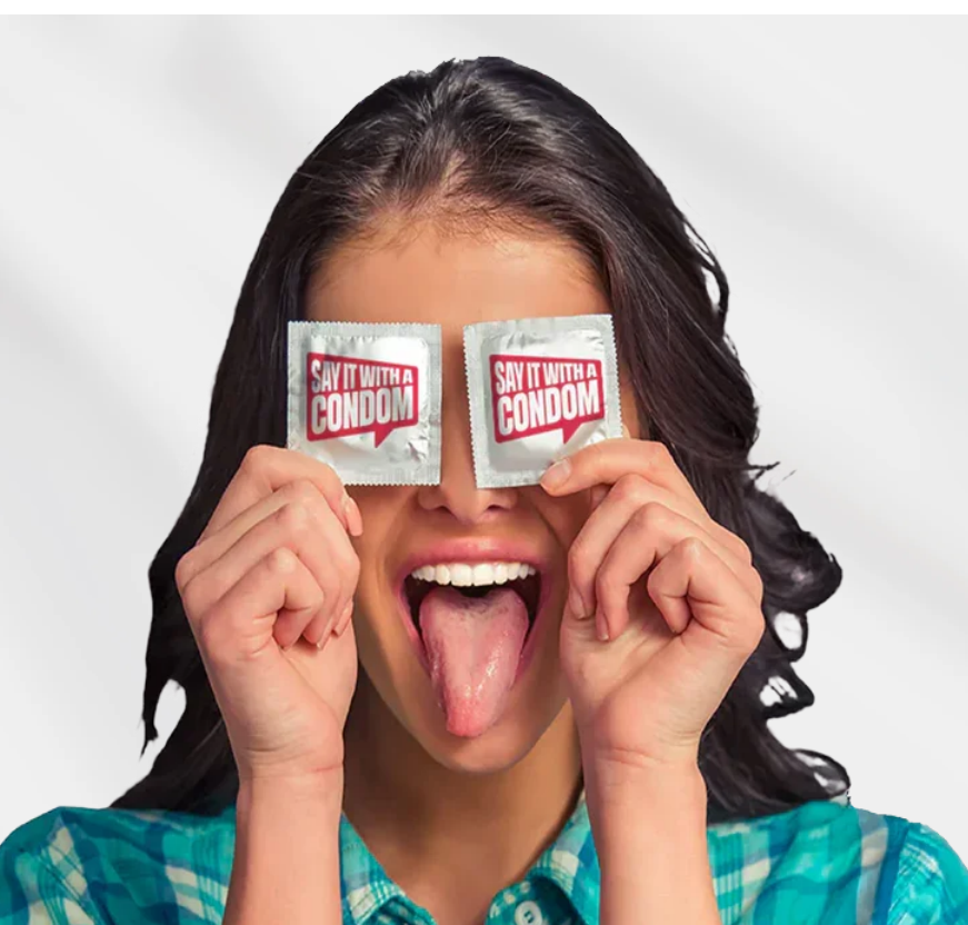 Woman holding two Say It With A Condom packets over her eyes